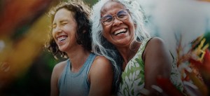 Duas mulheres sorrindo e se divertindo em um ambiente externo. Elas representam momentos de felicidade e conexão familiar.