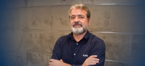 renato gomes, superintendente de venda consultiva, cruzando os braços ao lado de uma parede de concreto.