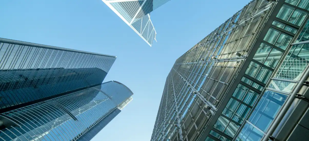 Imagem de arranha-céus de escritórios modernos em uma cidade, com uma perspectiva de baixo para cima, refletindo o céu azul claro e vidro.