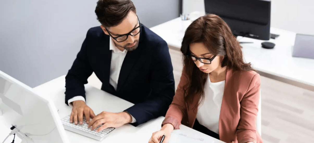 mulher fazendo auditoria ao lado de um homem mexendo no computador