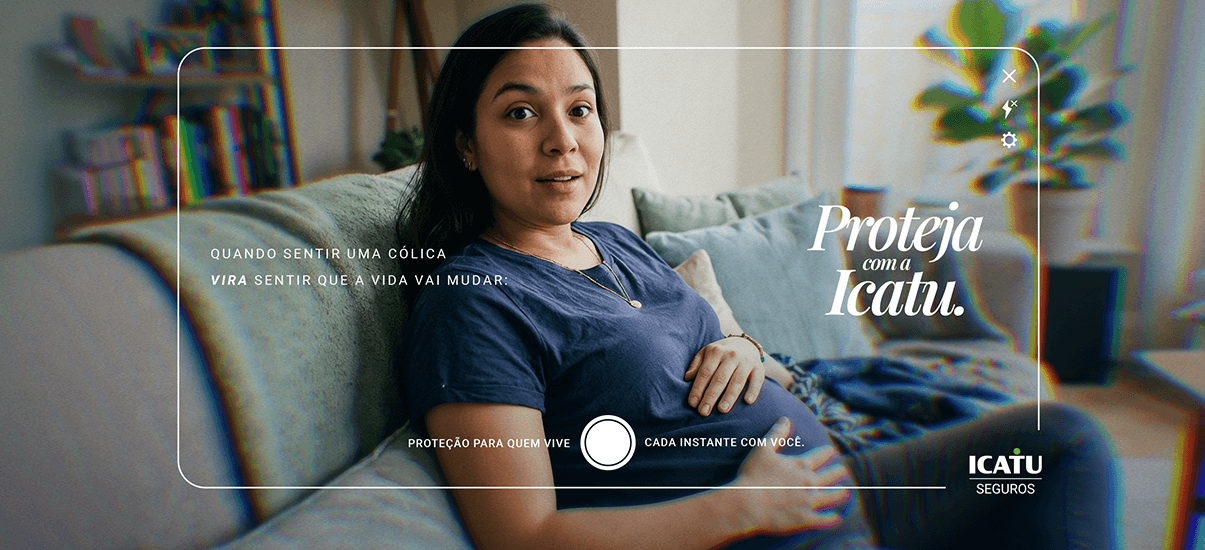Mulher grávida sentada no sofá em casa, promovendo proteção com ICATU Seguros, transmitindo segurança para quem vive momentos especiais.